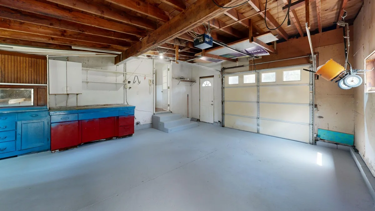 Inside a garage: ceiling opener, its rail running to a sectional door with windows, and the side tracks