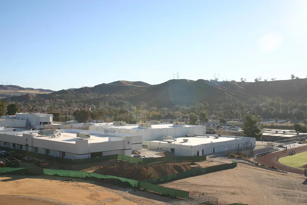 School campus buildings with dry brown hills rising behind them