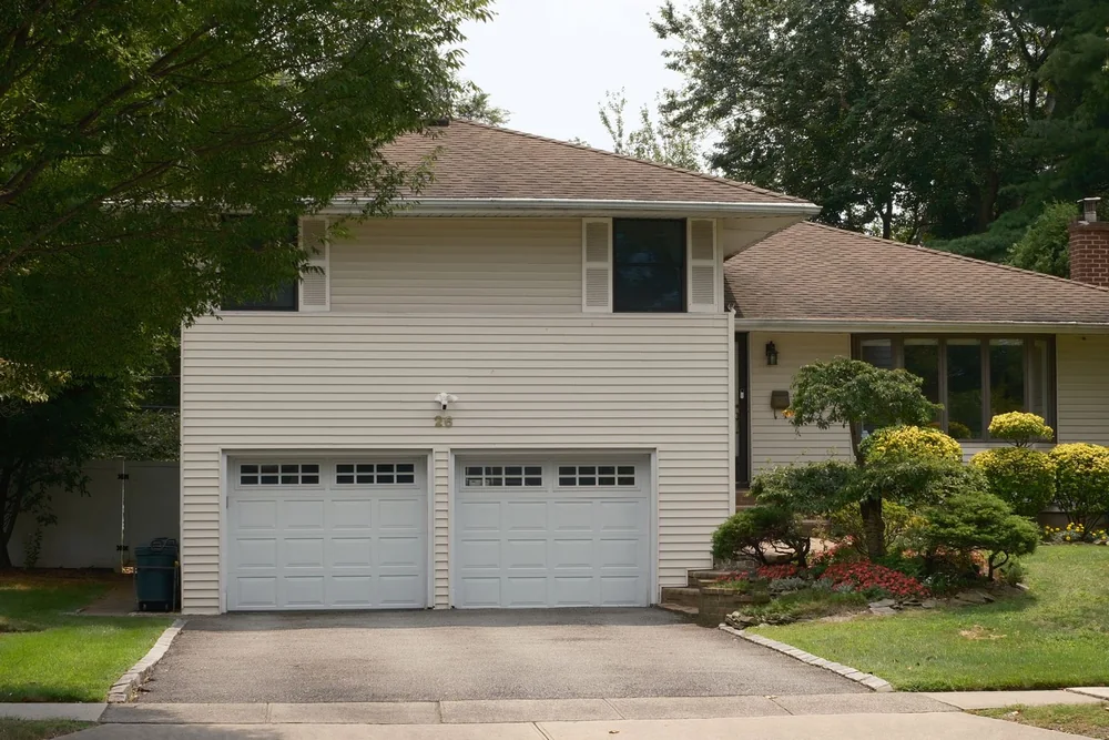 Split-level house with two white garage doors